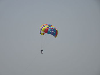 Low angle view of people paragliding against sky