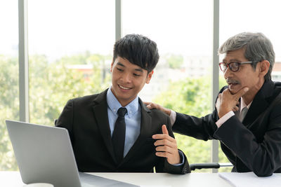 Smiling young man using laptop on mobile phone