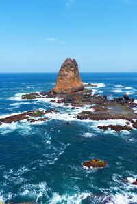 Rock formation in sea against blue sky