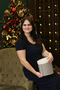 Portrait of young woman standing by christmas tree