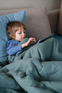 Cute boy relaxing on sofa at home