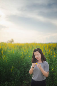 Portrait of beautiful young woman standing on field