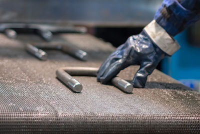 Cropped hand of worker holding metal on table