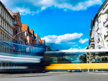 Blurred motion of cars on street in city against sky