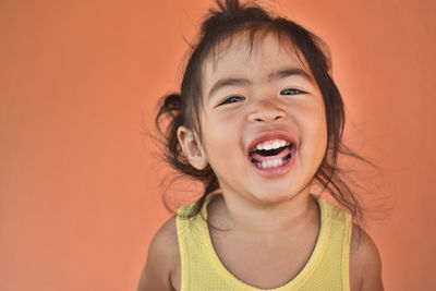 Portrait of cheerful girl against orange background