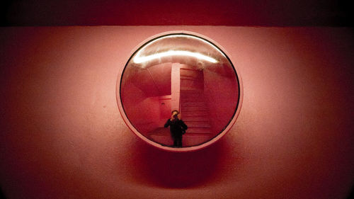 Reflection of man standing in illuminated mirror