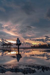 Woman standing against sea during sunset