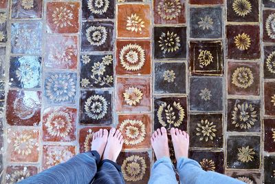 Low section of friends standing on patterned tiled floor