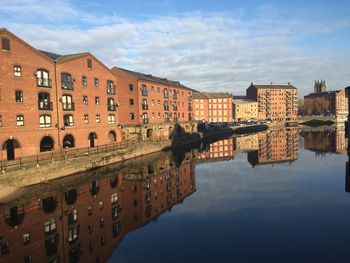 Canal by old buildings against sky