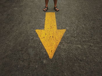 Low section of person standing on road sign