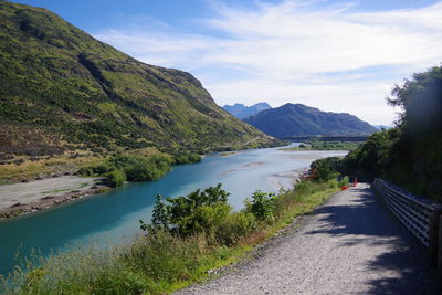 Scenic view of road by mountains against sky