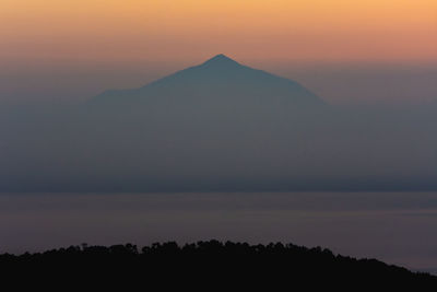 Scenic view of silhouette mountains against orange sky