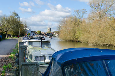 Boats moored by lake against sky