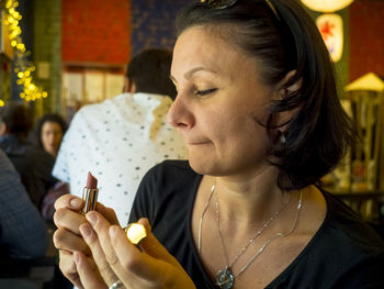 Woman holding lipstick in restaurant