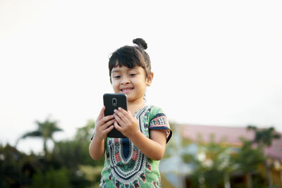 Girl using phone against sky