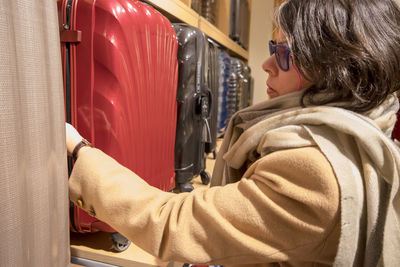 Side view of mature woman buying suitcase in store