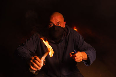 Portrait of man standing against black background