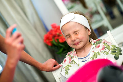 Cropped hands of beautician spraying water on girl at spa