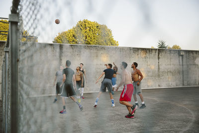 Male friends practicing basketball in court