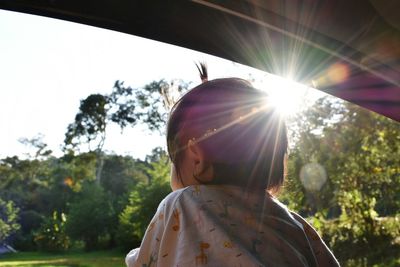 Close-up of baby girl looking at view through car window during sunny day