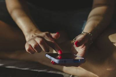 Woman texting using mobile phone, hands with red nail polish manicure in frame. online shopping.