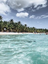 People swimming in pool at beach against sky