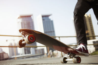 Low section of man skateboarding in city against sky