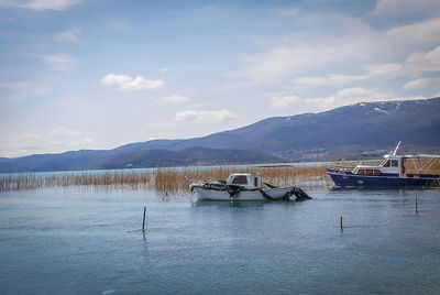 Sailboats moored in lake against sky