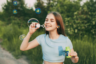 Portrait of smiling young woman holding bubbles