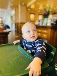 Cute baby boy sitting on high chair at home