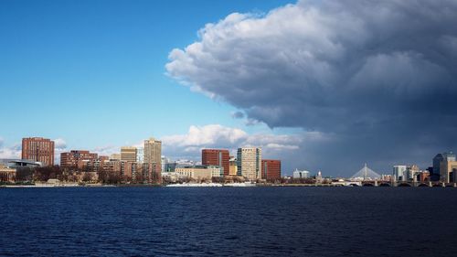 Sea by cityscape against sky