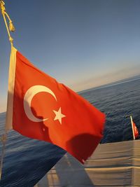 Red flag on sea against clear blue sky