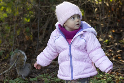 Cute baby girl wearing warm clothing standing on land