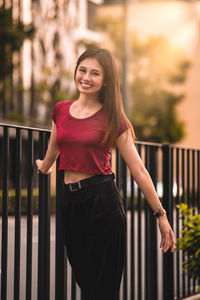 Portrait of smiling woman walking by railing