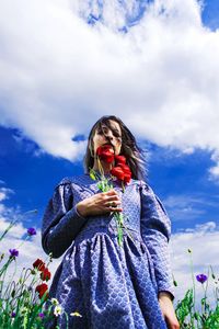 Low angle view of woman standing against blue sky