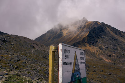 Information sign on mountain against sky