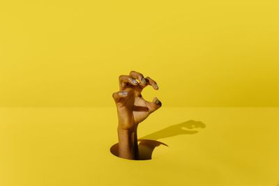 Midsection of shirtless man against yellow background