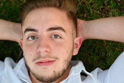Close-up portrait of young man lying outdoors