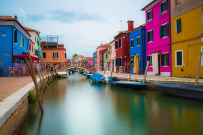 Boats moored in canal amidst buildings in city