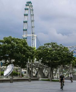 People walking on road against cloudy sky