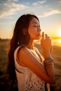 Beautiful asian girl in boho style standing at sunset on beach.