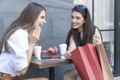 Smiling young woman drinking water from while sitting on table