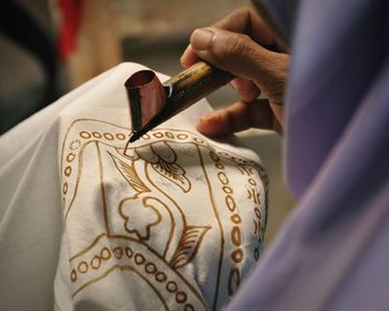 Cropped hand of artisan making design on textile