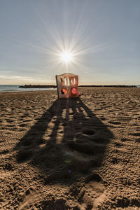 Sunlight falling on sand at beach against sky