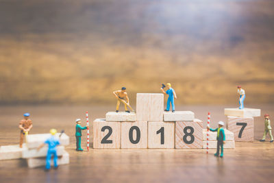 Figurines working over toy blocks with numbers on table