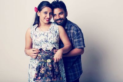 Smiling man touching belly of pregnant woman against white background