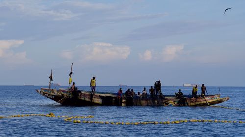 People enjoying in sea against sky