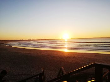 Scenic view of beach against clear sky during sunset