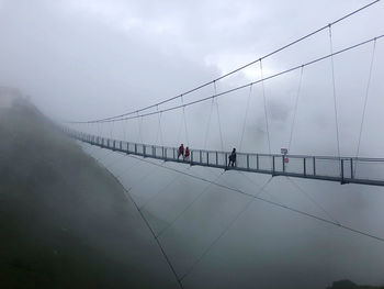 People on bridge against sky