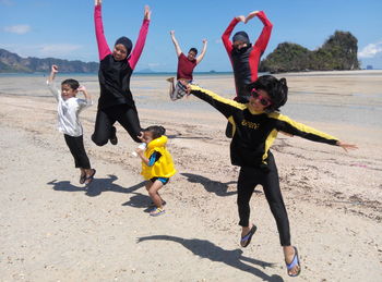 Full length of children playing on beach against sky